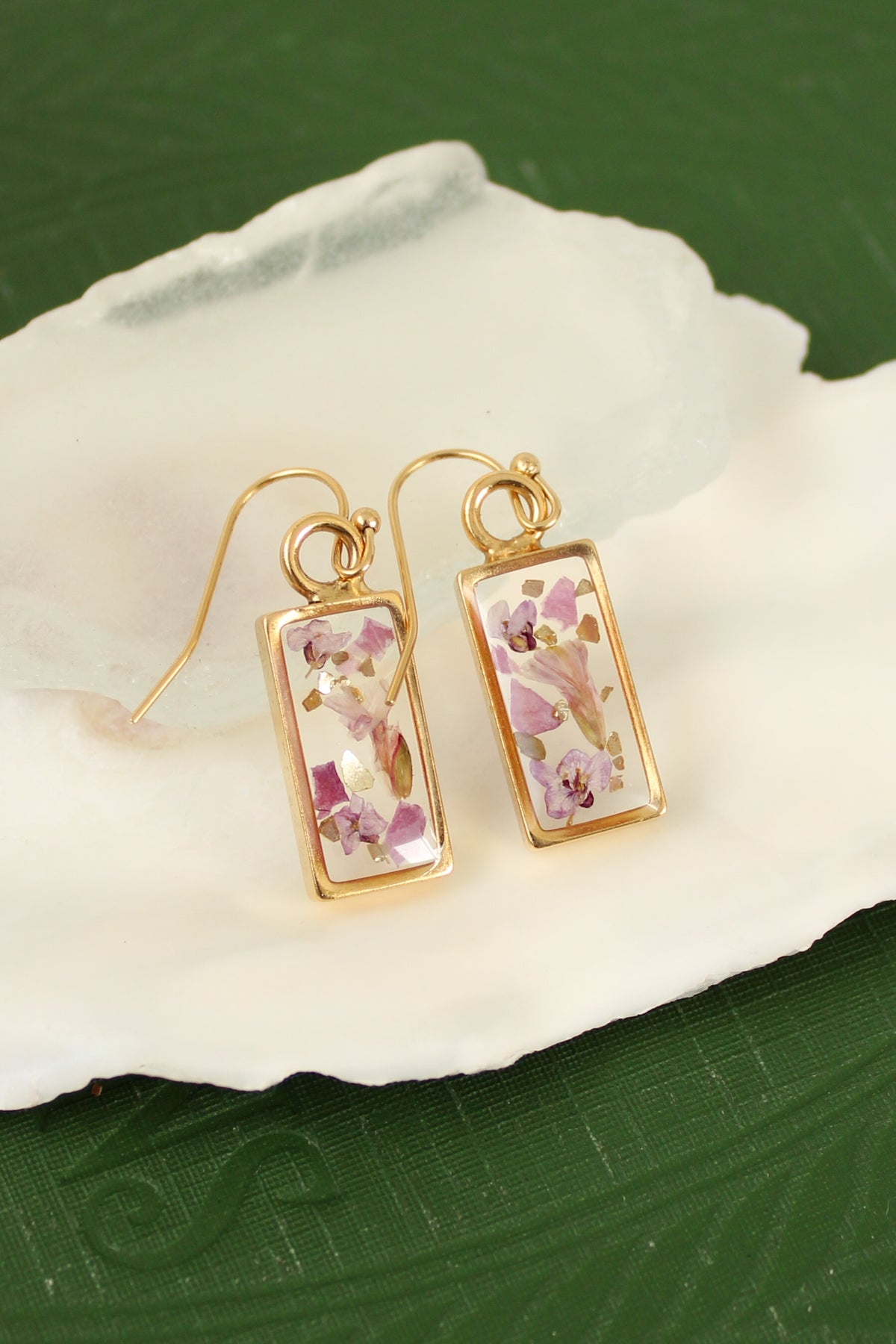 handmade rectangular shaped dangle earrings made from clear resin and pink flowers, with shiny gold glass flecks