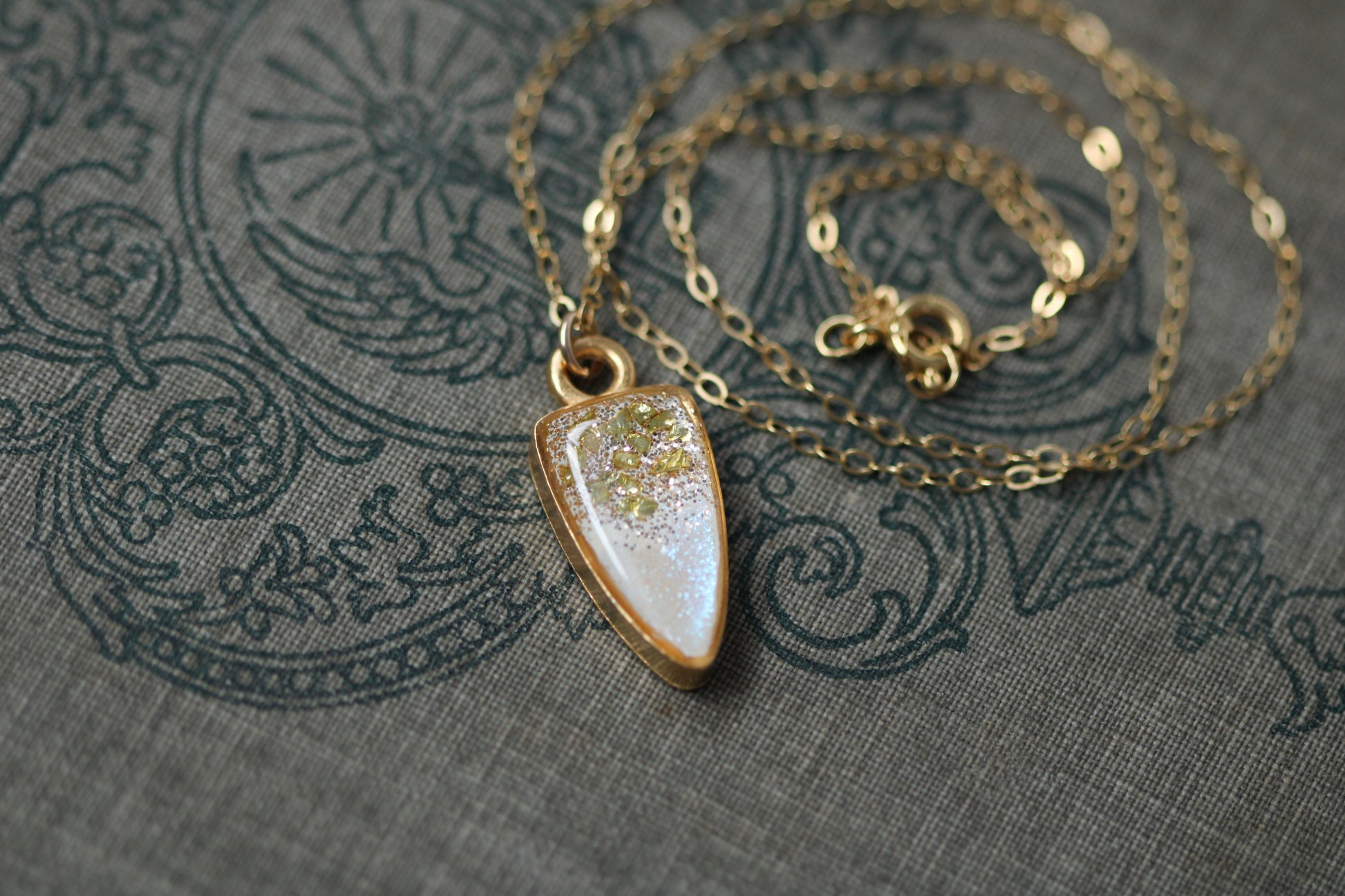 small gold sparkly pendant necklace displayed on book, 18 inch gold filled chain