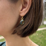 model wearing handmade dark green and gold small circle shaped dangle earrings with dried flowers and resin
