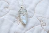 silver sparkly pendant necklace on sterling silver chain displayed on white fabric