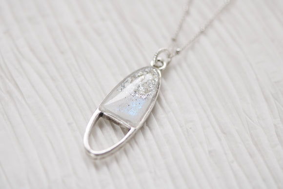 Silver oval shaped necklace with sparkle on white background
