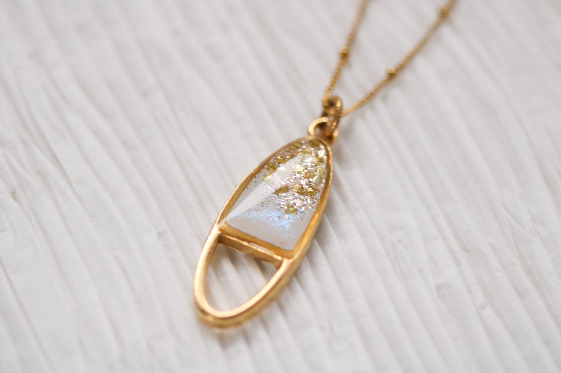 gold sparkly oval necklace on white background