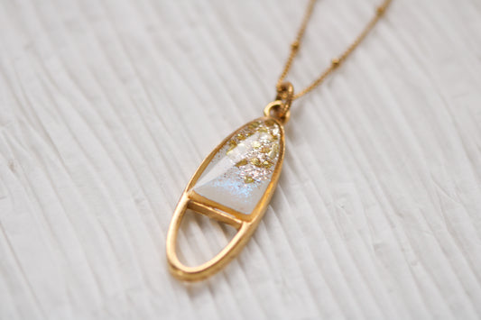 gold sparkly oval necklace on white background