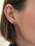 model wearing gold and dark green circle stud earrings with white dried alyssum flower handmade in clay with resin