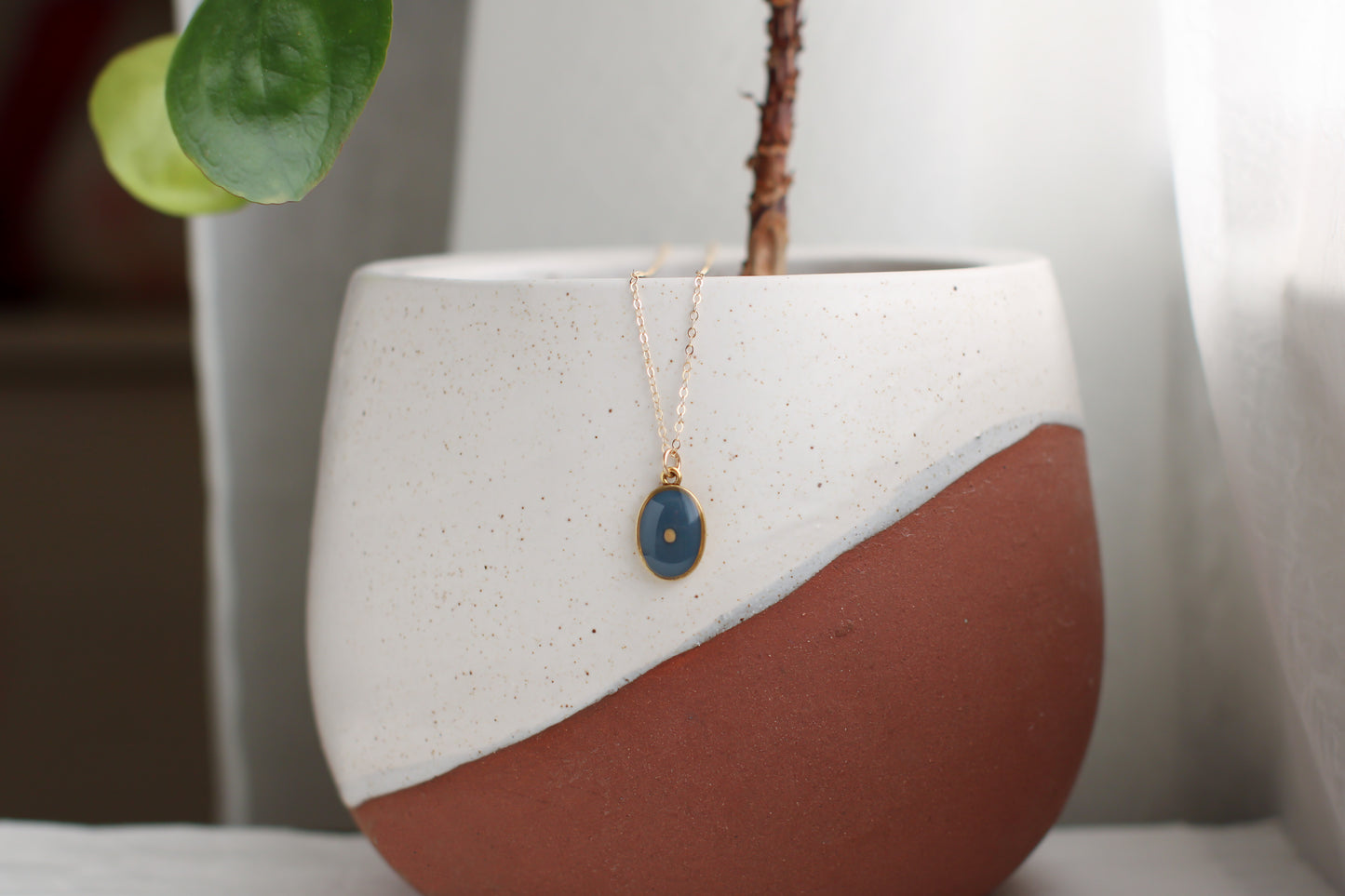 mustard seed necklace gold oval with gray blue background and mustard seed 
