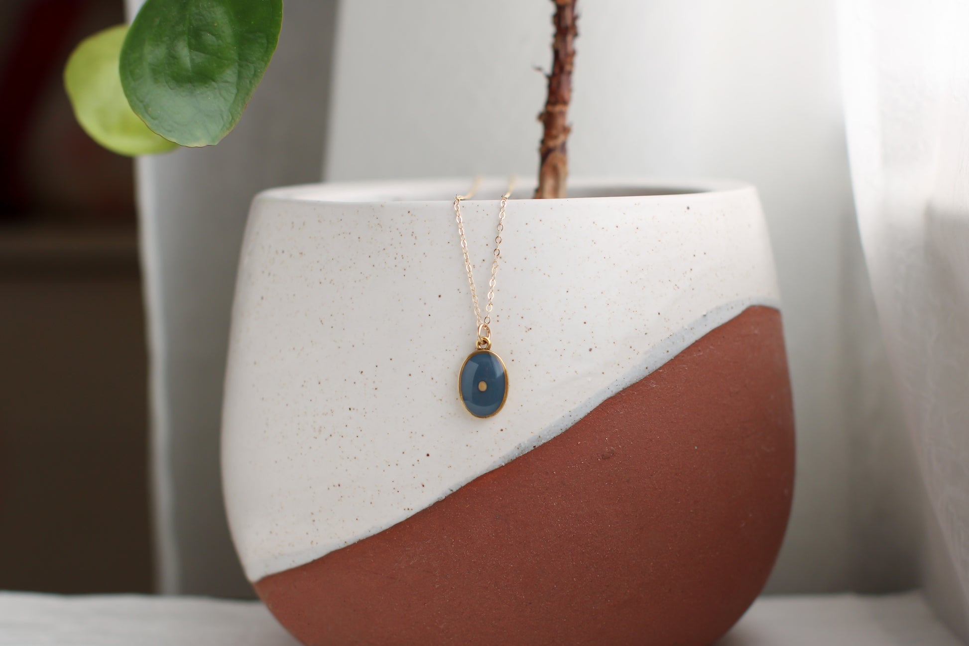 mustard seed necklace gold oval with gray blue background and mustard seed 