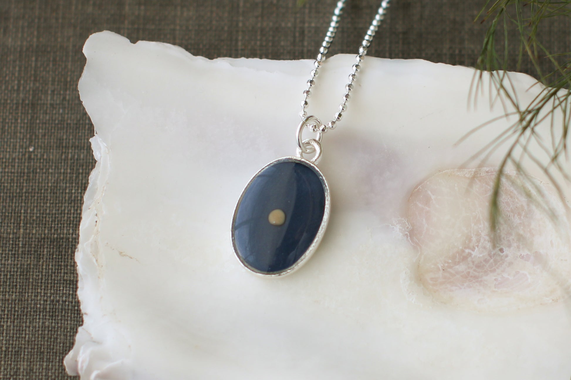close up mustard seed oval necklace in silver